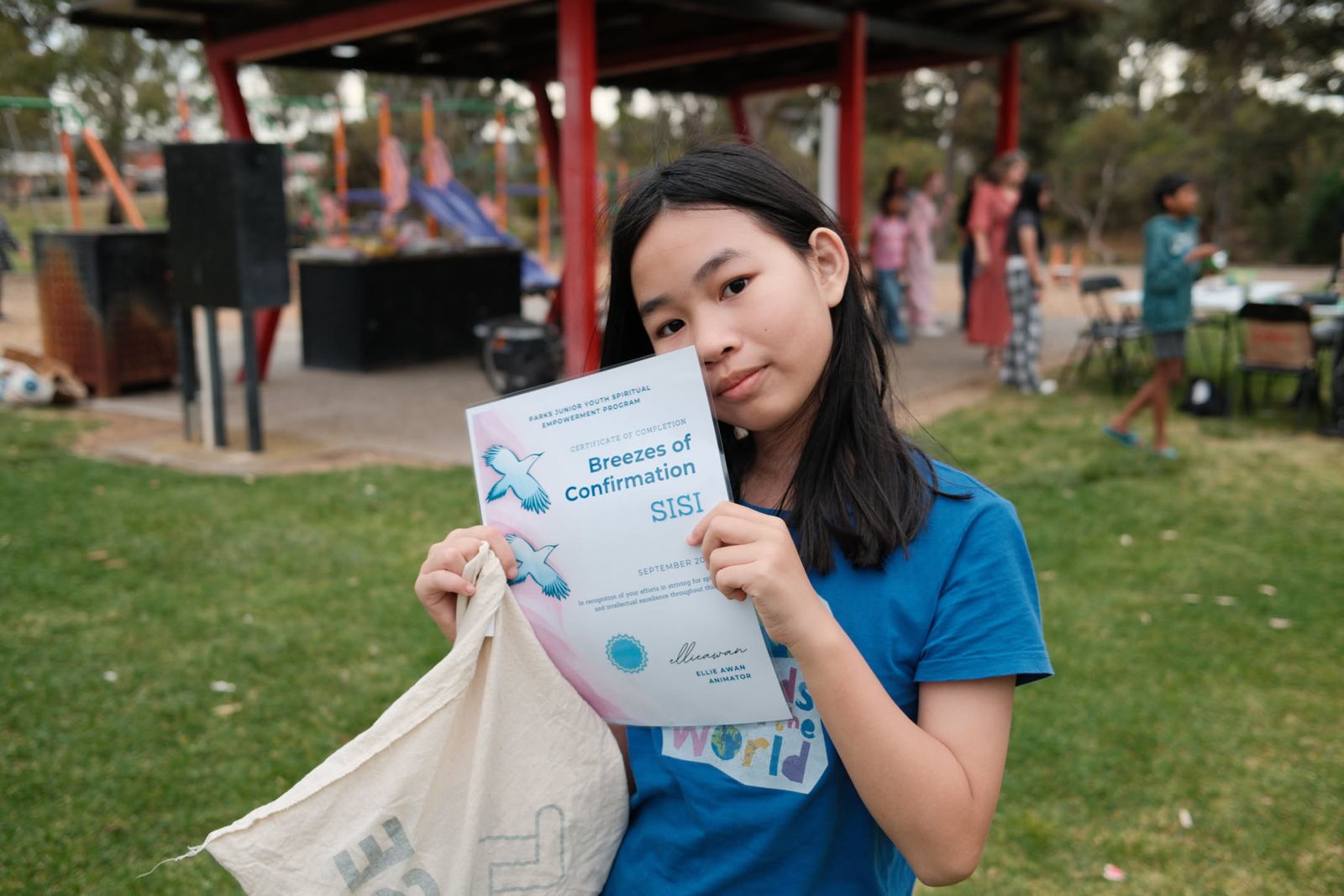 A junior youth holding her Breezes of Confirmation certificate