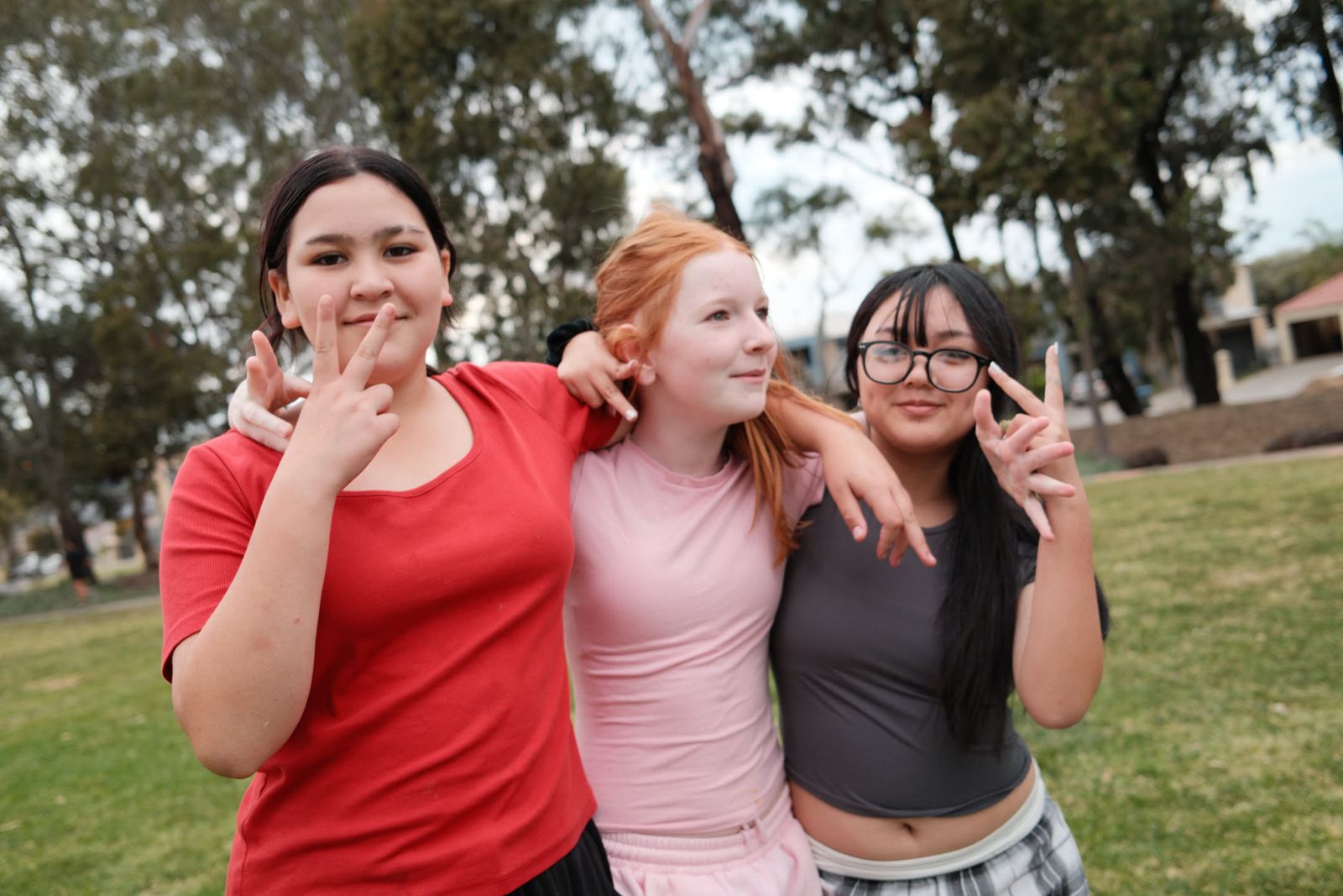 Three friends posing together at the park